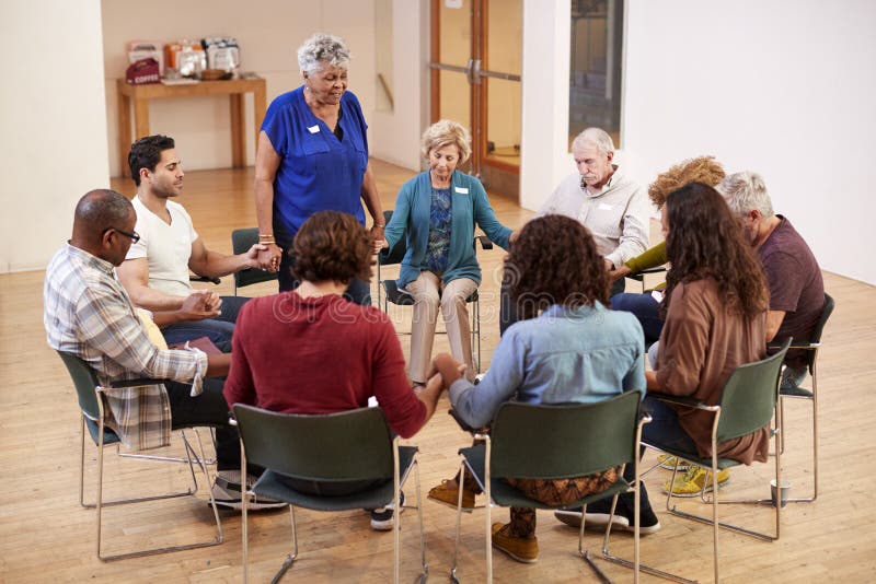 Les gens tenant des mains et priant lors de la réunion de groupe de travail de bible au centre social image stock