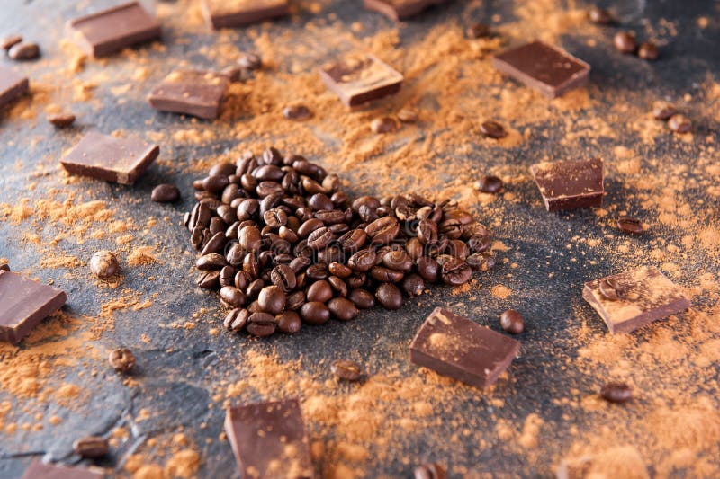Les grains de café rôtis sous forme de coeur sur le fond en pierre foncé avec absorbent le cacao, des morceaux de chocolat et des photographie stock libre de droits Les grains de café rôtis sous forme de coeur sur le fond en pierre foncé avec absorbent le cacao, des morceaux de chocolat et des photographie stock libre de droits