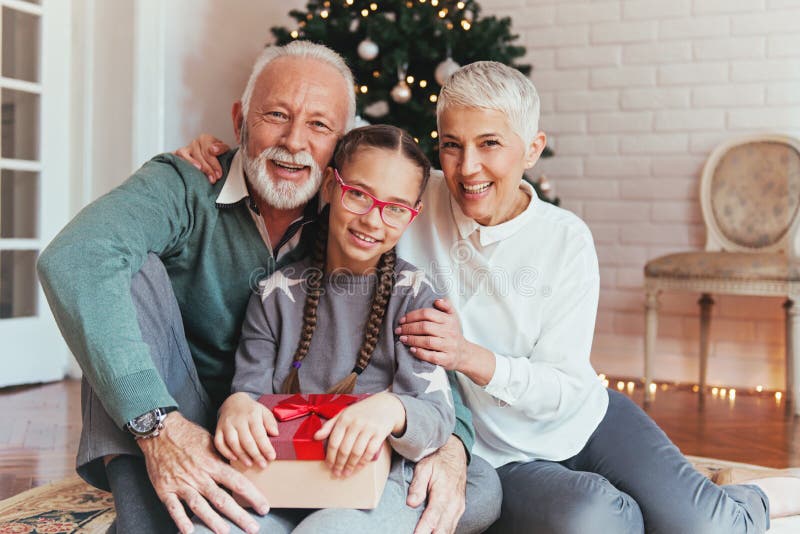 Les grands-parents et leur petite-fille se sont réunis autour d'un arbre de Noël, souriant photo libre de droits Les grands-parents et leur petite-fille se sont réunis autour d'un arbre de Noël, souriant photo libre de droits