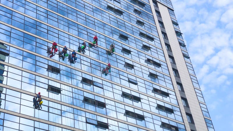 Les grimpeurs nettoient les fenêtres de l'extérieur de l'immeuble en nettoyant les vitrages de la façade d'un immeuble de plusieur banque de vidéos