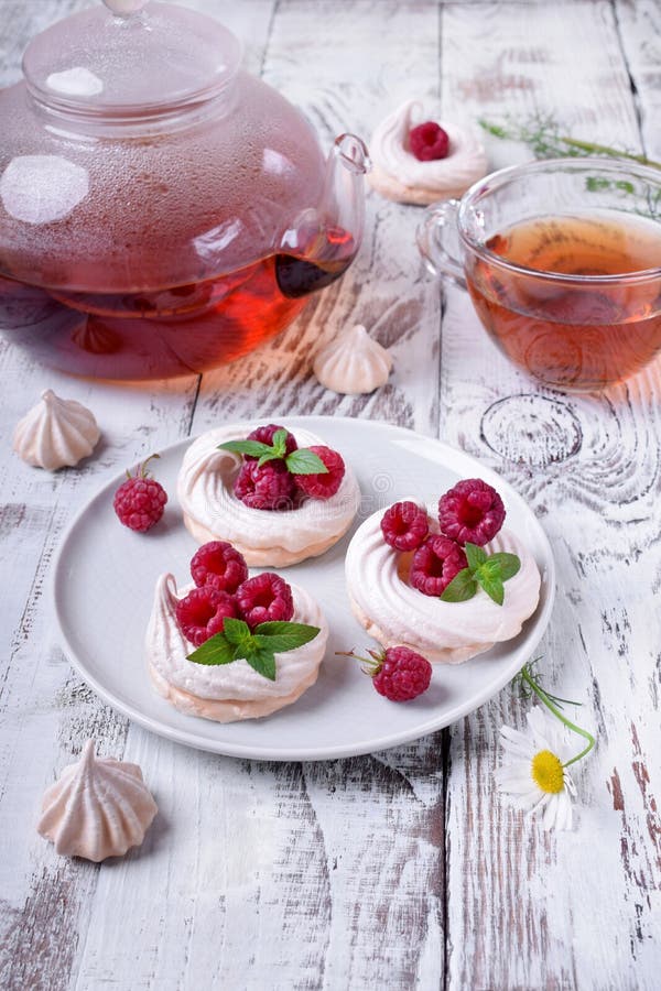 Les gâteaux de Mini Pavlova ont complété avec les framboises et la menthe photo libre de droits Les gâteaux de Mini Pavlova ont complété avec les framboises et la menthe photo libre de droits