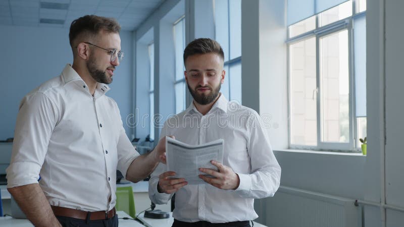 Les hommes barbus parlent du travail du papier dans un bureau banque de vidéos