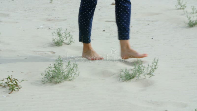 Les jambes d'une belle fille va sur le sable