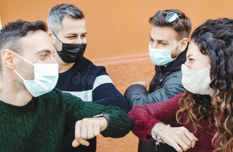 Young friends greet each other using their elbow wearing surgical masks - Social distancing and coronavirus prevention concept - focus on the elbows. Young friends greet each other using their elbow wearing surgical masks - Social distancing and coronavirus prevention concept - focus on the elbows.