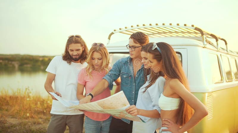Les jeunes avec la carte près de la voiture en été. Groupe d'amis de sourire heureux. banque de vidéos