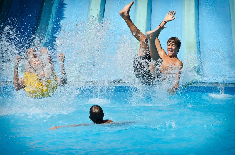 Les jeunes ayant l'amusement sur des glissières d'eau dans le parc d'aqua photographie stock Les jeunes ayant l'amusement sur des glissières d'eau dans le parc d'aqua photographie stock