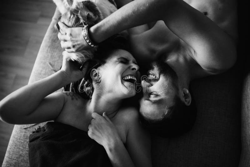Les jeunes beaux couples se trouvent sur le divan et rire Chien photographie stock libre de droits Les jeunes beaux couples se trouvent sur le divan et rire Chien photographie stock libre de droits