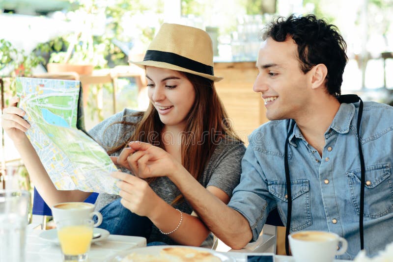 Les jeunes couples de touristes regardent une carte image libre de droits Les jeunes couples de touristes regardent une carte image libre de droits