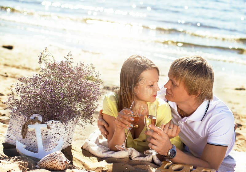 Les jeunes couples heureux appréciant le pique-nique sur la plage et ont le bon Ti images stock Les jeunes couples heureux appréciant le pique-nique sur la plage et ont le bon Ti images stock