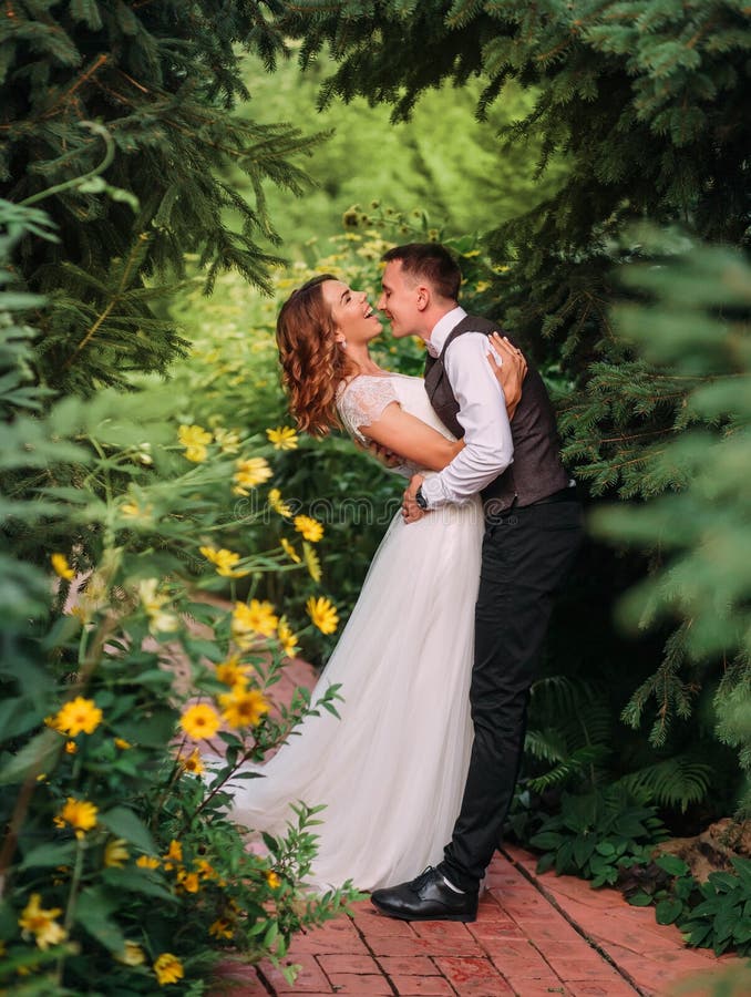 Les jeunes couples mignons du marié et de la jeune mariée dans une longue robe l'épousant blanche sont jouants et riants dans un photo stock Les jeunes couples mignons du marié et de la jeune mariée dans une longue robe l'épousant blanche sont jouants et riants dans un photo stock
