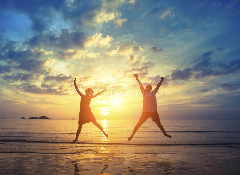 Les jeunes couples sautant sur la mer échouent pendant le coucher du soleil étonnant photo libre de droits Les jeunes couples sautant sur la mer échouent pendant le coucher du soleil étonnant photo libre de droits