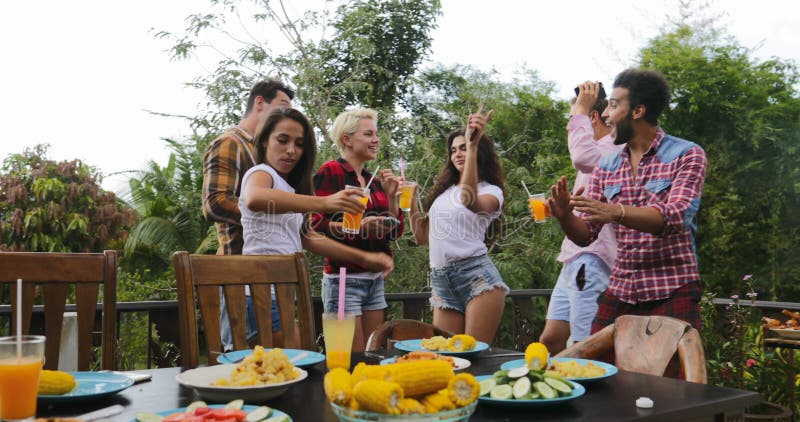 Les jeunes dansant faisant cuire le rassemblement gai de groupe d'amis de barbecue sur la terrasse d'été ayant la partie banque de vidéos