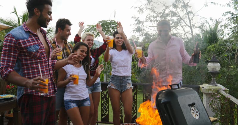 Les jeunes dansant tout en faisant cuire le rassemblement gai de groupe heureux de barbecue sur la terrasse d'été ayant la partie clips vidéos