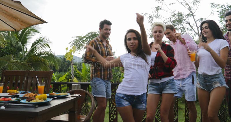 Les jeunes dansant tout en faisant cuire le rassemblement gai de groupe heureux de barbecue sur la terrasse d'été ayant la partie banque de vidéos