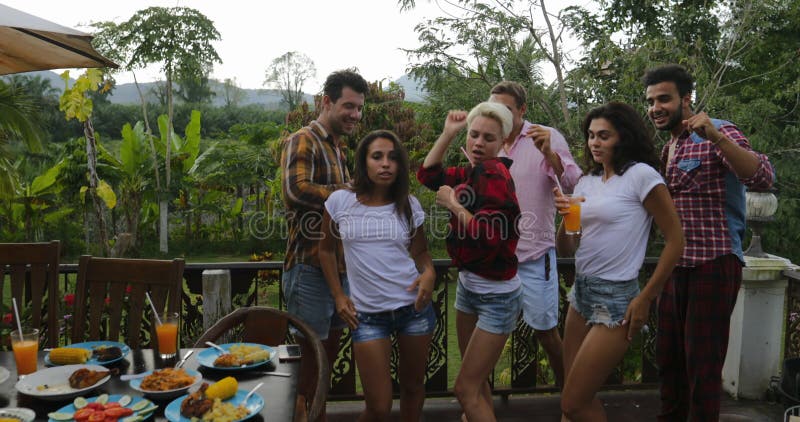 Les jeunes dansant tout en faisant cuire le rassemblement gai de groupe heureux de barbecue sur la terrasse d'été ayant la partie banque de vidéos