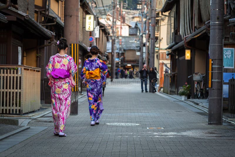 Les jeunes femmes utilisant le kimono japonais traditionnel marchent sur la rue de Gion