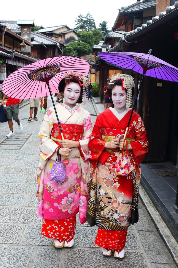 Les jeunes filles japonaises se sont habillées dans la coutume du ` s de geisha faisant un tour dans les routes pierre-pavées de photographie stock libre de droits Les jeunes filles japonaises se sont habillées dans la coutume du ` s de geisha faisant un tour dans les routes pierre-pavées de photographie stock libre de droits