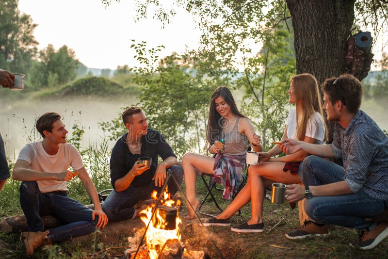 Les jeunes gais chauffant près du feu de camp photo stock