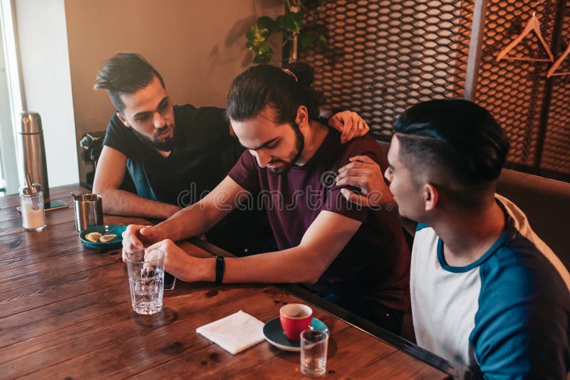 Les jeunes hommes de support encouragent leur ami navré de douleur Les types Arabes l'encouragent dans le restaurant Concept d'am