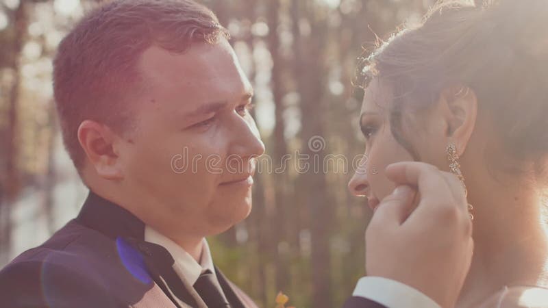 Les jeunes mariés dans l'amour, regardant l'un l'autre dans une belle forêt verte au soleil Visages en gros plan des nouveaux mar