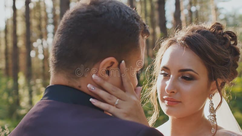 Les jeunes mariés dans l'amour, regardant l'un l'autre dans une belle forêt verte au soleil Visages en gros plan des nouveaux mar