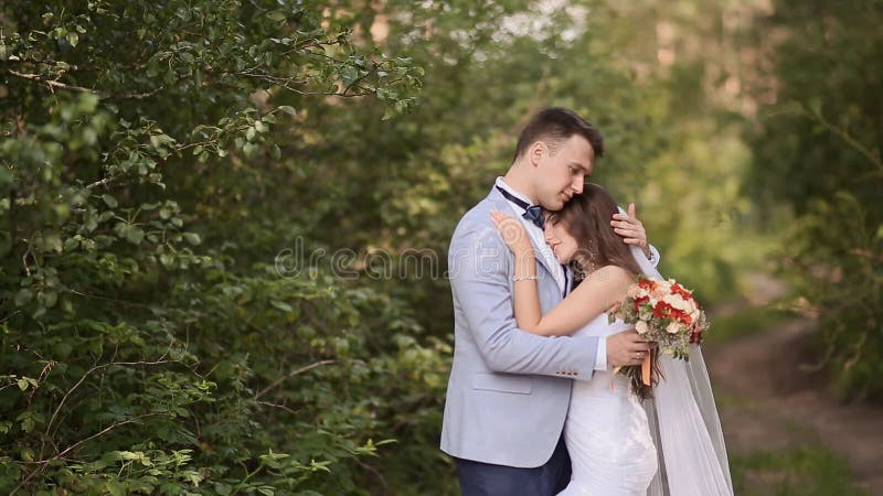 Les jeunes mariés dans la forêt la jeune mariée mettent sa tête sur l'épaule du ` s de marié Le marié étreint sa jeune mariée Un