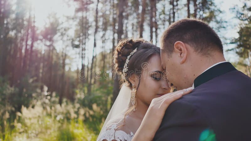 Les jeunes mariés ensemble dans une danse parmi les pins dans la forêt au soleil Jour du mariage Moments de bonheur