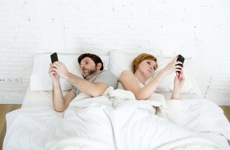 Les jeunes ont marié des couples utilisant leur téléphone portable dans le lit s'ignorant dans des problèmes de transmission de r photos stock Les jeunes ont marié des couples utilisant leur téléphone portable dans le lit s'ignorant dans des problèmes de transmission de r photos stock