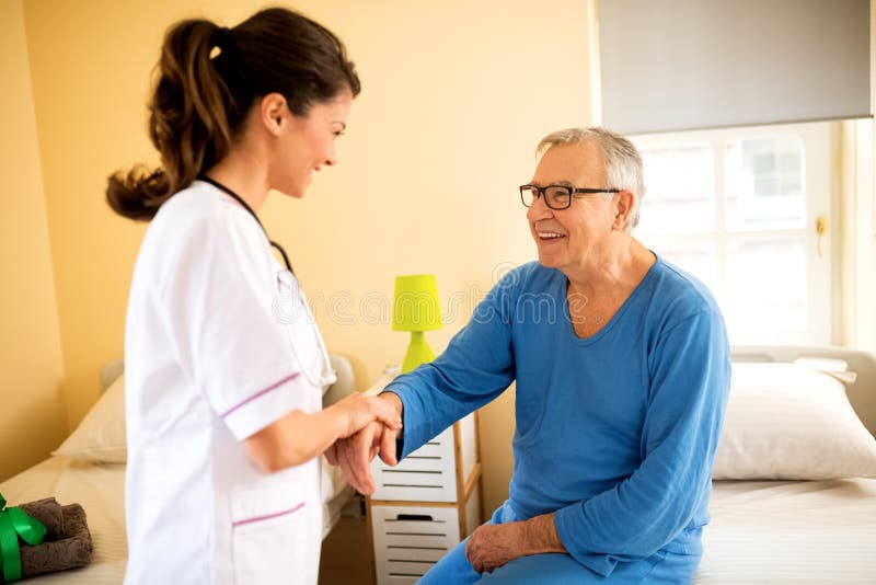 Les jeunes soigneux soignent le patient supérieur d'aides pour se lever photos libres de droits Les jeunes soigneux soignent le patient supérieur d'aides pour se lever photos libres de droits