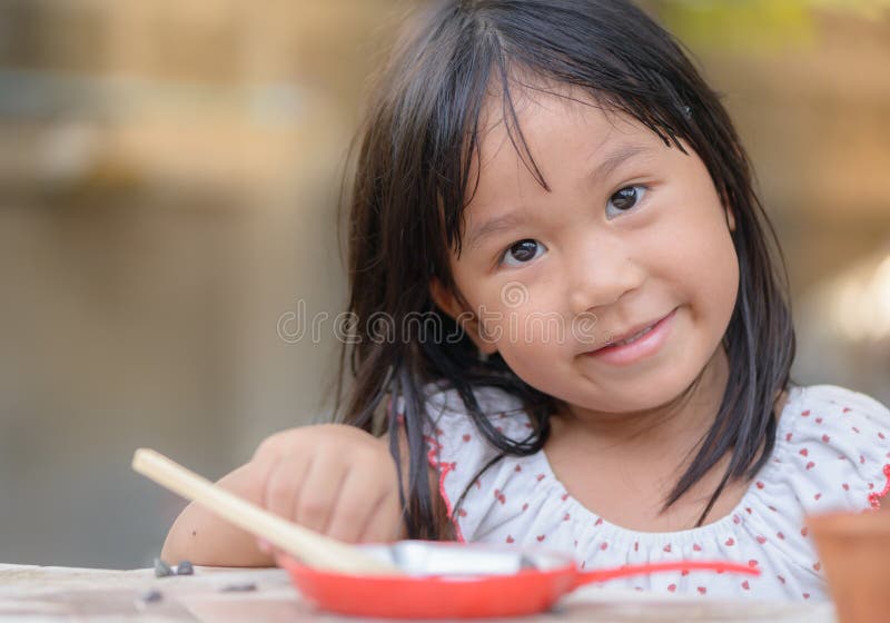 Les jeux de sourire de petite fille font cuire sur la table images stock Les jeux de sourire de petite fille font cuire sur la table images stock