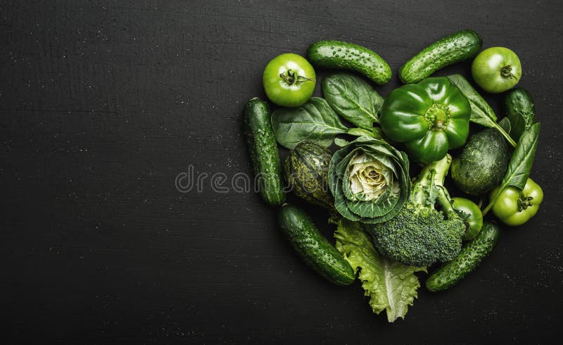 Les légumes verts frais ont arrangé dans la forme de coeur sur une table en pierre noire images stock Les légumes verts frais ont arrangé dans la forme de coeur sur une table en pierre noire images stock