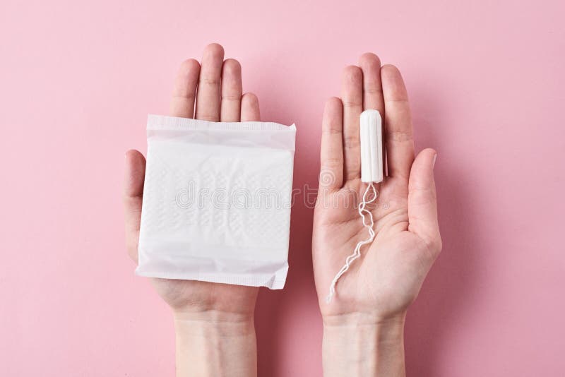 Les mains de femme tiennent la protection sanitaire et le tampon sur un fond rose photos libres de droits Les mains de femme tiennent la protection sanitaire et le tampon sur un fond rose photos libres de droits