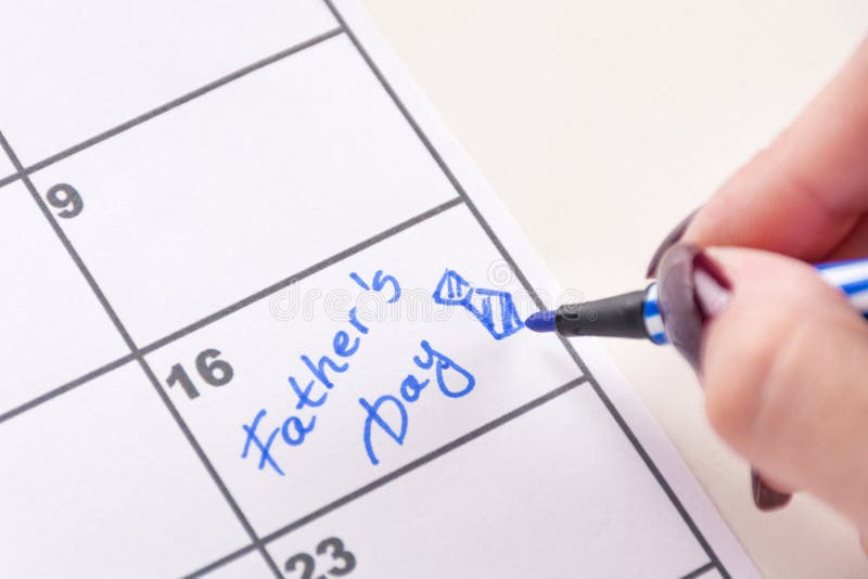 Les mains de fille avec le stylo de feutre écrit la fête des pères de mot et l'arc de lien de dessin dans le calendrier images stock Les mains de fille avec le stylo de feutre écrit la fête des pères de mot et l'arc de lien de dessin dans le calendrier images stock