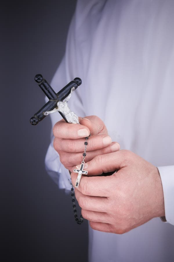 Les mains de l'homme avec un cap blanc, le crucifix et un chapelet noir images stock Les mains de l'homme avec un cap blanc, le crucifix et un chapelet noir images stock