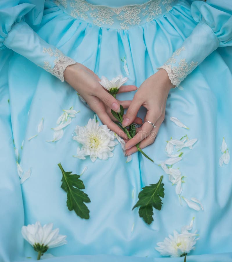 Les mains de la femme avec la fleur closeut sur une robe bleue photo stock