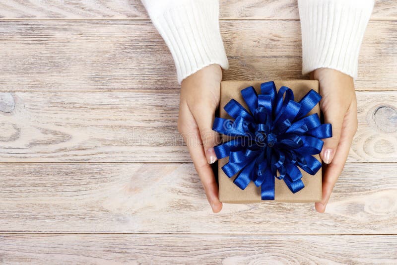 Les mains de la femme tiennent Noël ou le boîte-cadeau décoré de nouvelle année boîte-cadeau avec un grand arc bleu images libres de droits Les mains de la femme tiennent Noël ou le boîte-cadeau décoré de nouvelle année boîte-cadeau avec un grand arc bleu images libres de droits
