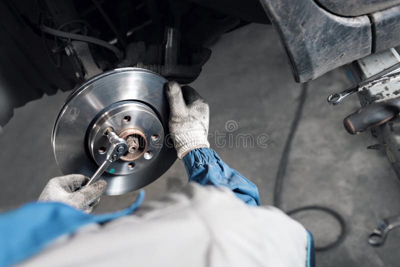 Les mains de mécanicien de voiture remplacent des freins dans le garage