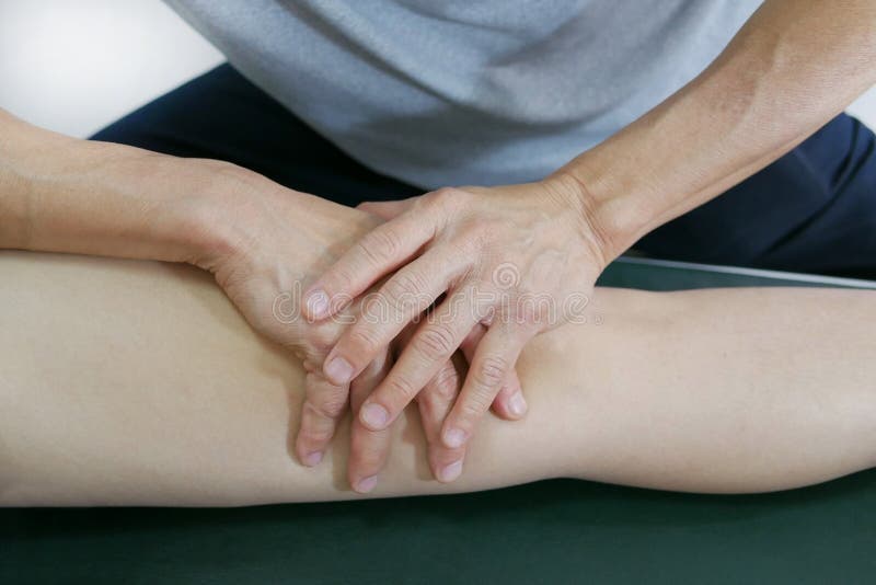 Les mains de physiothérapeute traitent le genou au patient sur le lit images libres de droits Les mains de physiothérapeute traitent le genou au patient sur le lit images libres de droits