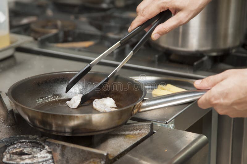 Les mains du cuisinier, grillant la crevette photo stock Les mains du cuisinier, grillant la crevette photo stock