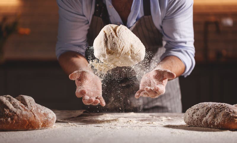 Les mains du mâle du ` s de boulanger malaxent la pâte