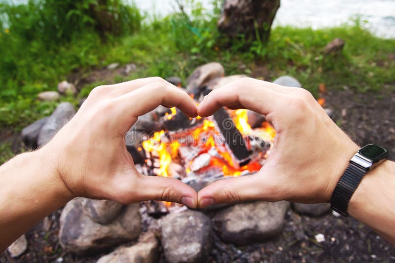 Men`s hands are warming around the campfire in the forest. Men`s hands are warming around the campfire in the forest