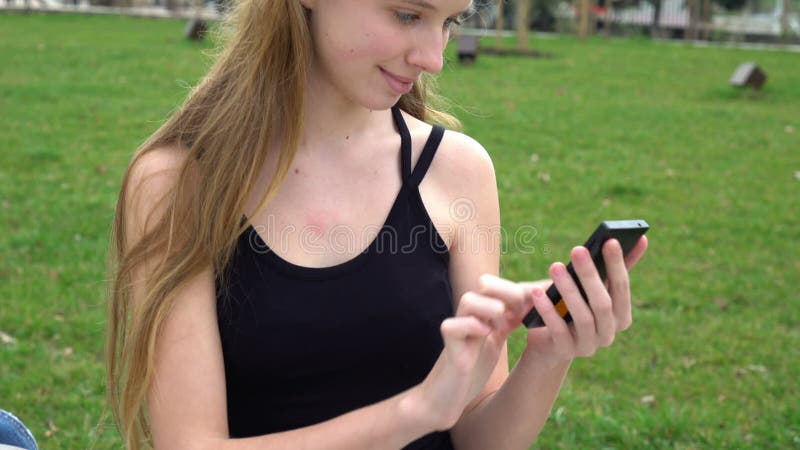 Les mains en gros plan de femme utilisant l'écran tactile téléphonent dehors en parc de ville banque de vidéos