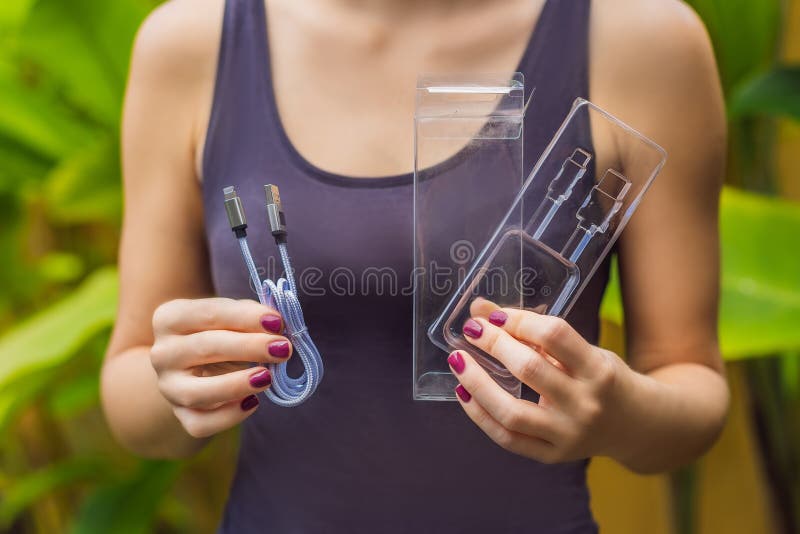 Les mains femelles ont imprimé un nouveau fil pour charger le téléphone Le fil a été emballé dans un grand nombre de conditionnem photo libre de droits Les mains femelles ont imprimé un nouveau fil pour charger le téléphone Le fil a été emballé dans un grand nombre de conditionnem photo libre de droits