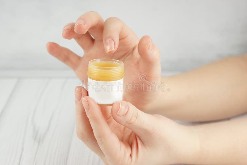 Les mains femelles tiennent un pot avec un agent cosmétique et commencent à appliquer un baume à la peau photographie stock libre de droits Les mains femelles tiennent un pot avec un agent cosmétique et commencent à appliquer un baume à la peau photographie stock libre de droits