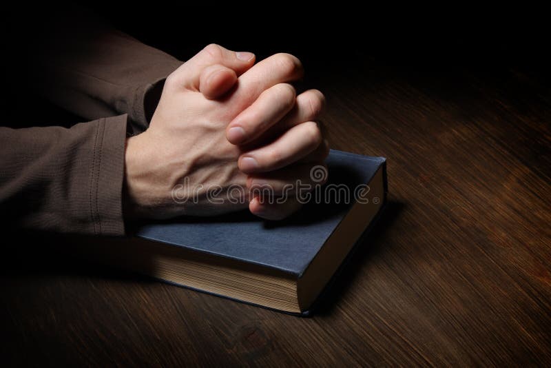 Les mains se sont pliées dans la prière au-dessus d'une bible sainte images stock