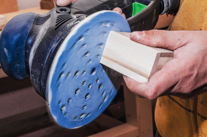 Les mains un homme polit une partie en bois avec une machine de meulage carpe photographie stock