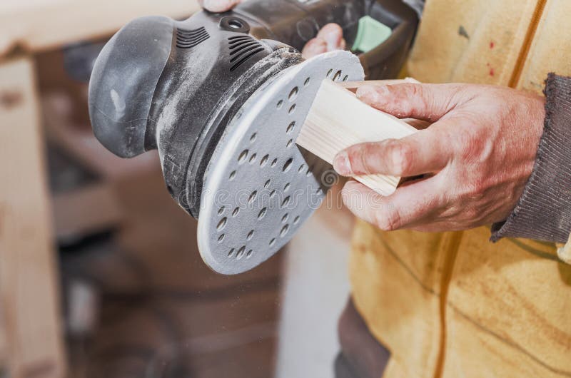 Les mains un homme polit une partie en bois avec une machine de meulage carpe photo libre de droits