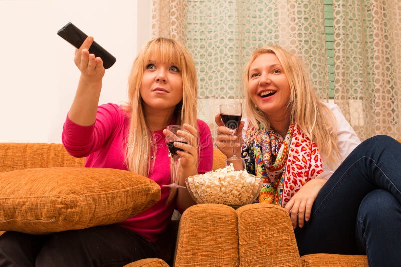 Les meilleurs amis à la maison regardant la TV et buvant le style de vin rétro ont filtré l'image images stock Les meilleurs amis à la maison regardant la TV et buvant le style de vin rétro ont filtré l'image images stock