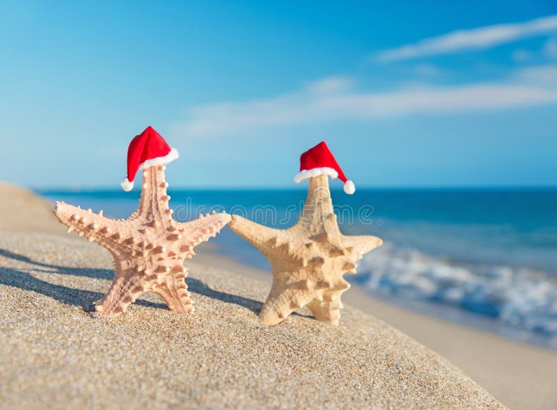les Mer-étoiles couplent dans des chapeaux de Santa marchant à la plage. Concept de vacances photos libres de droits les Mer-étoiles couplent dans des chapeaux de Santa marchant à la plage. Concept de vacances photos libres de droits