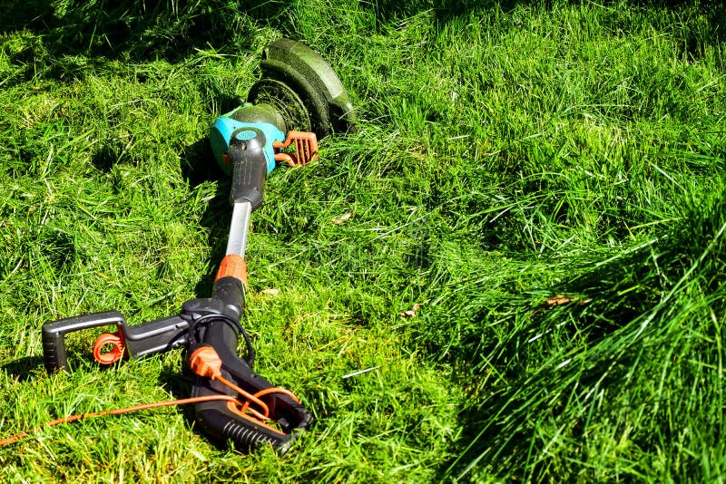 Les moments simples de la vie, travail ordinaire dans le jardin - homme ?quilibrant l'herbe avec le trimmer r?sistant dans le jar photographie stock Les moments simples de la vie, travail ordinaire dans le jardin - homme ?quilibrant l'herbe avec le trimmer r?sistant dans le jar photographie stock